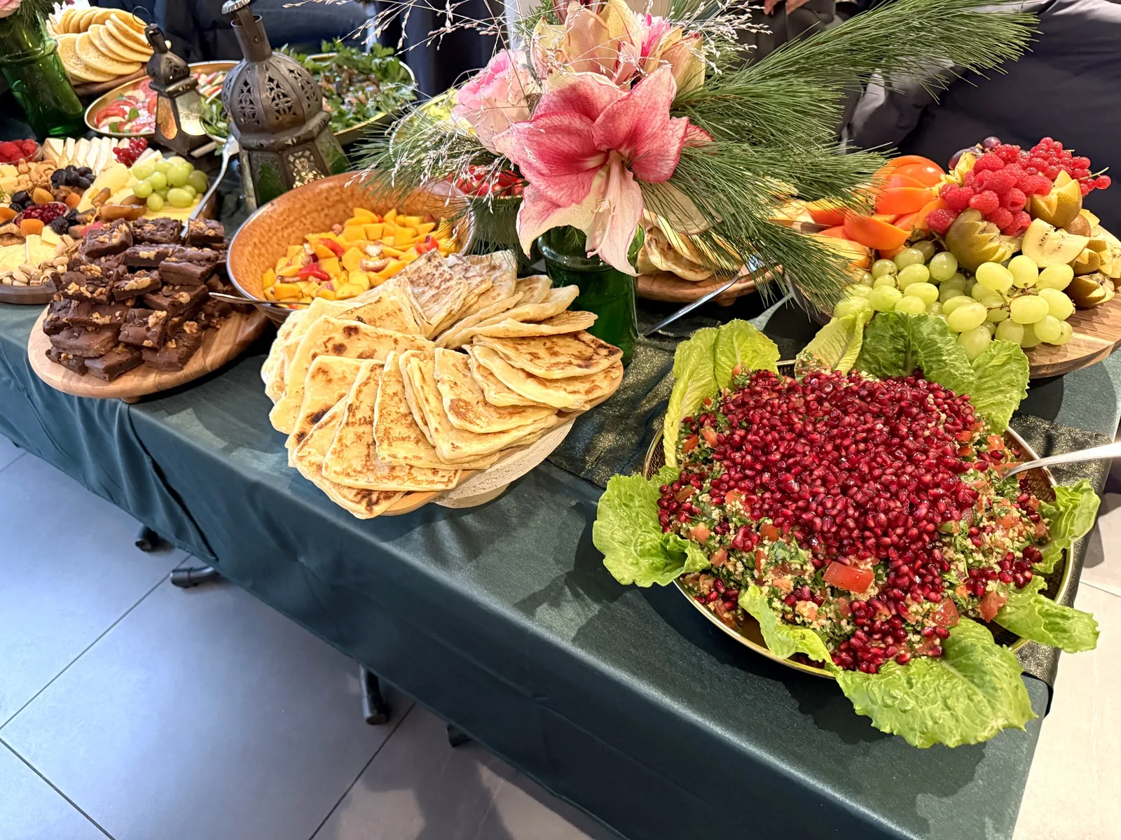 Catering-Buffet mit Blumen, Fladenbrot, Granatapfel-Salat und Obst