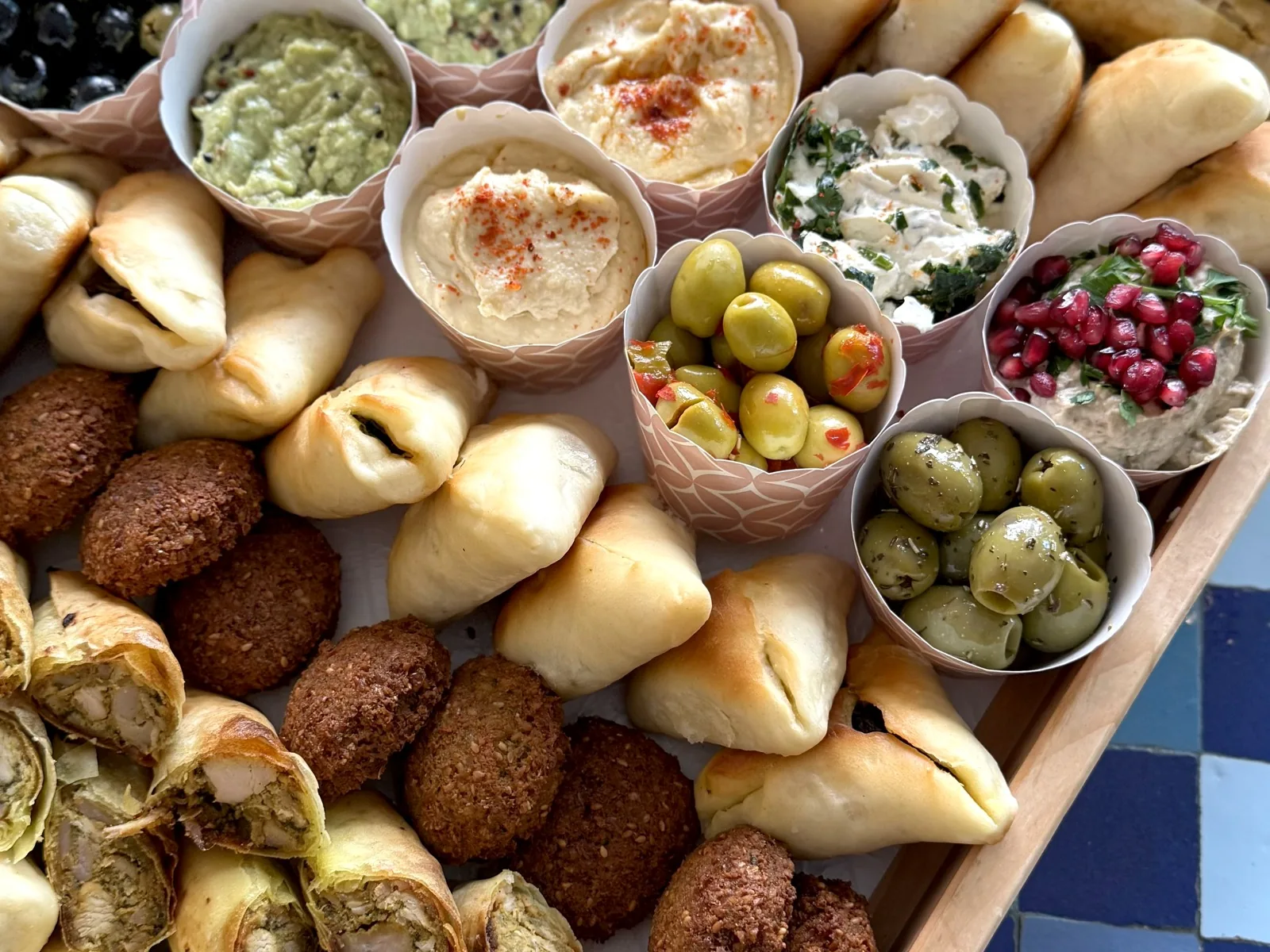 Fingerfood-Tablett mit Falafel, Teigtaschen, Oliven und Dips