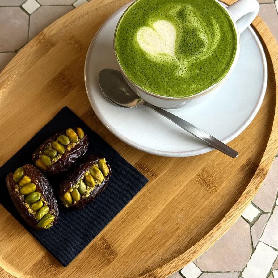 Matcha Latte mit Milchschaum-Herz und mit Pistazien gefüllte Datteln
