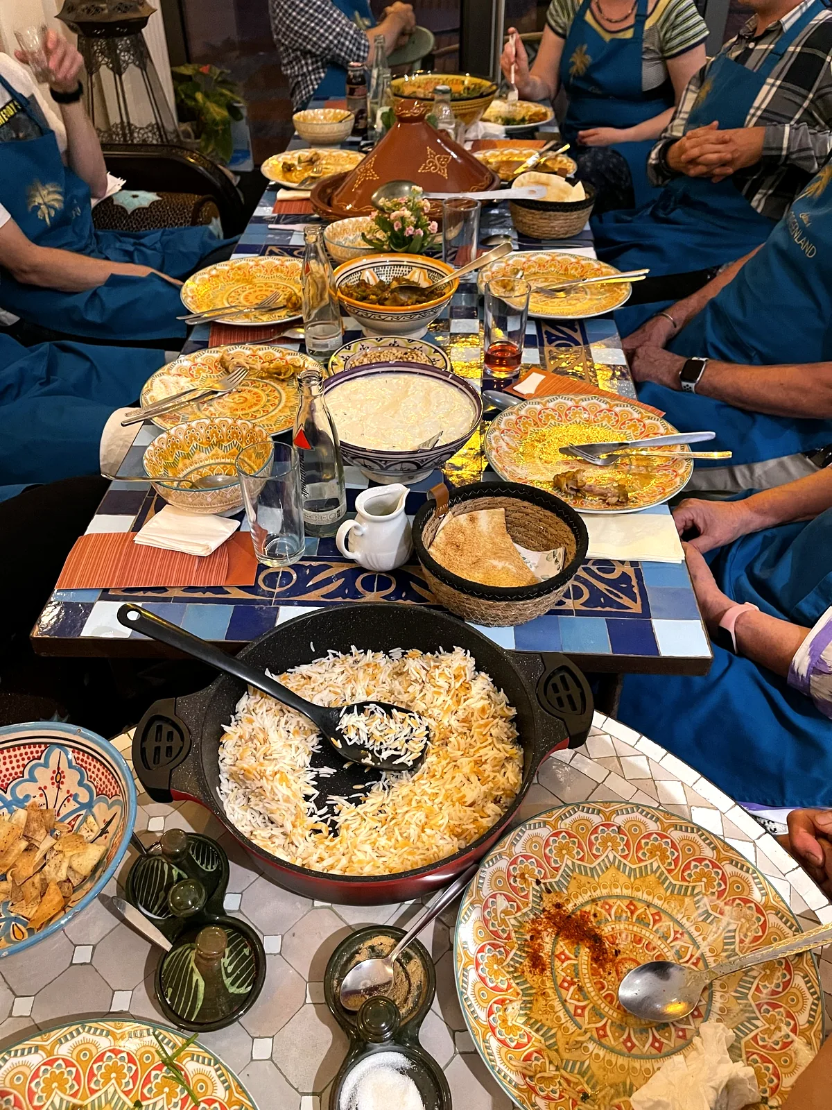 Lange gedeckte Tafel mit Reis, Salaten und Dips beim gemeinsamen Essen