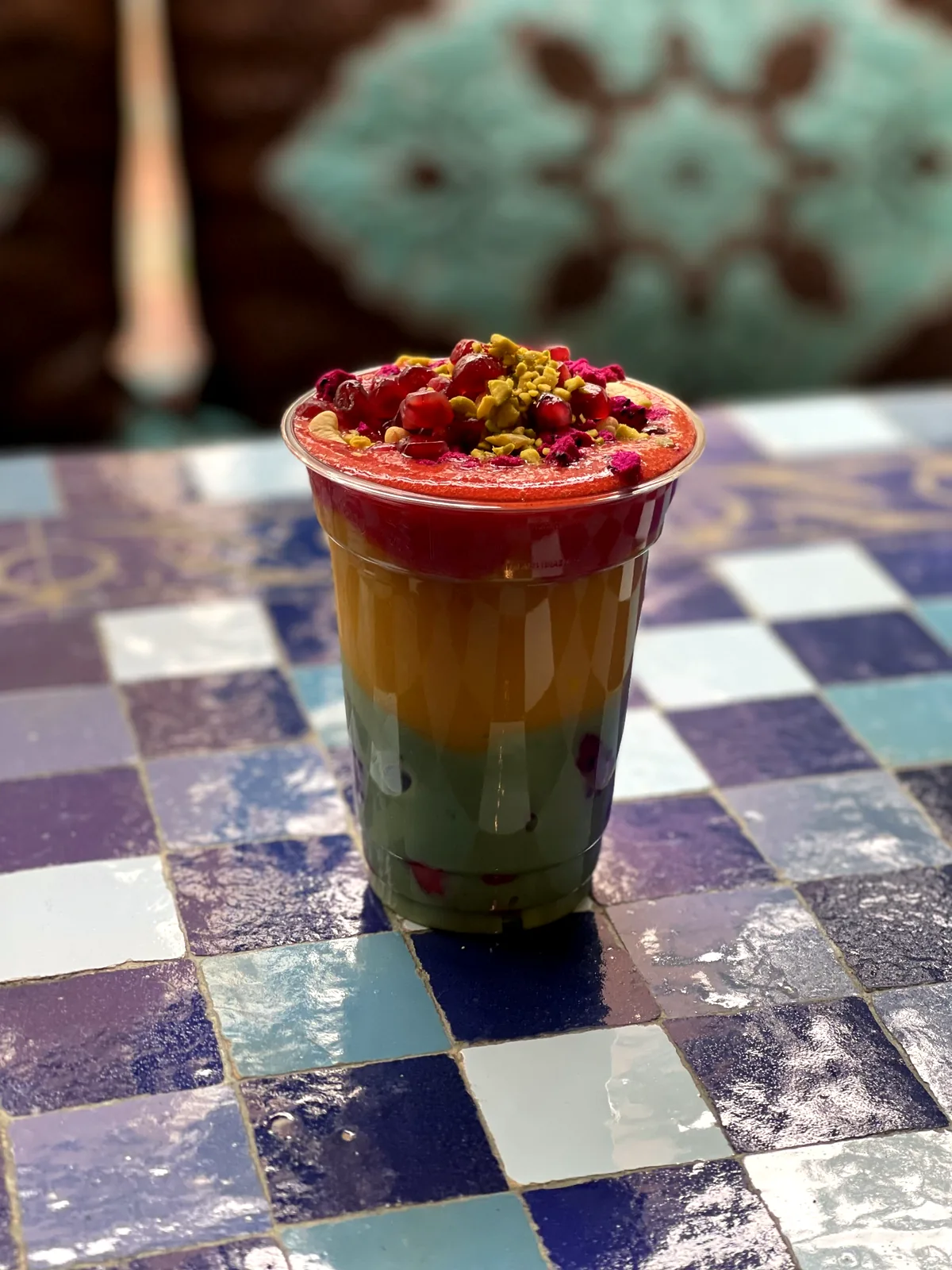 Geschichteter Smoothie mit Granatapfelkernen im Becher