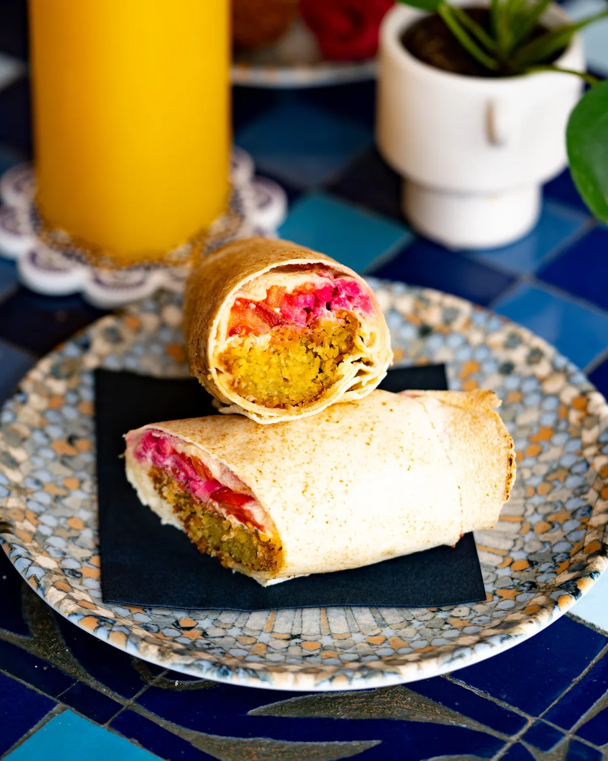 Zwei aufgeschnittene Falafel-Wraps auf einem Mosaikteller